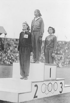 three women standing on top of a podium in front of an audience at a sporting event