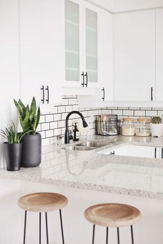 three stools sit in front of a kitchen counter with white cabinets and black accents