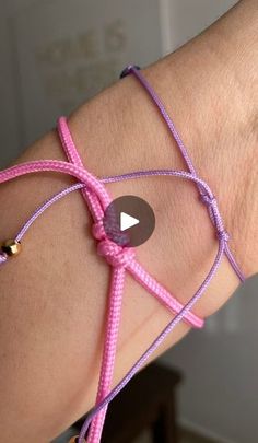 a woman's arm wearing pink and purple bracelets with an arrow on it