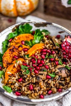 a white bowl filled with rice and vegetables on top of a table next to pumpkins