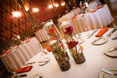 the table is set with white linens, silverware and red roses in vases