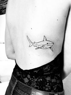 a black and white photo of a woman's back shoulder with a shark tattoo on it