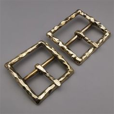 two metal buckles on a gray surface