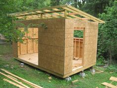 a small wooden shed sitting on top of a lush green forest covered in lots of wood planks