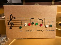 a card with music notes and buttons on it that says, we wish you a merry christmas