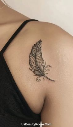 a woman's back with a tattoo on her shoulder and a feather in the middle