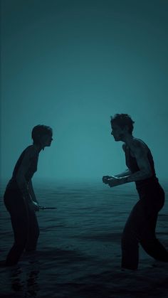 two people standing in the water with one holding something