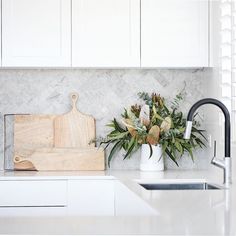 a kitchen counter with a cutting board and flowers in a vase next to the sink