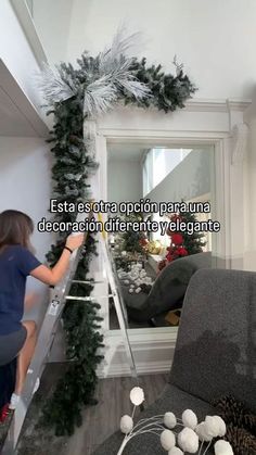 a woman on a ladder decorating a living room with christmas garland and poinsettis