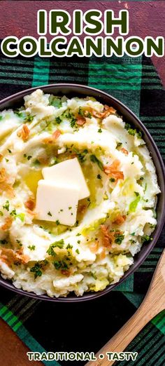 a bowl filled with mashed potatoes topped with butter and parsley next to a wooden spoon