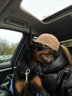 a woman sitting in the back seat of a car with a dog on her lap