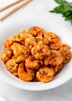 a white bowl filled with shrimp and garnished with parsley on the side