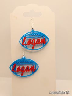 two earrings with the word logo on them are hanging from a card board in front of a white background