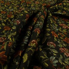 the fabric is black with red and green flowers on it, as well as an orange flower