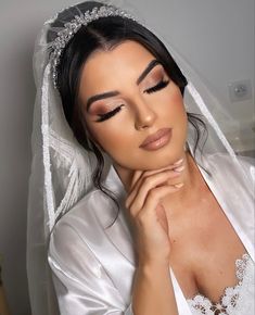 a woman wearing a bridal veil and holding her hand under her chin, posing for the camera