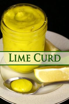 a jar of lime curd sitting on top of a white plate next to a slice of lemon