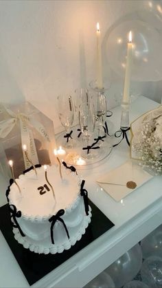 a white cake sitting on top of a table next to candles and other items in front of it