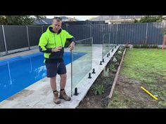 a man standing next to a swimming pool with poles in the ground and some water behind him