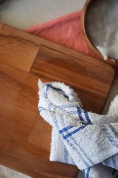 a wooden cutting board topped with a bowl of milk and a cloth on top of it