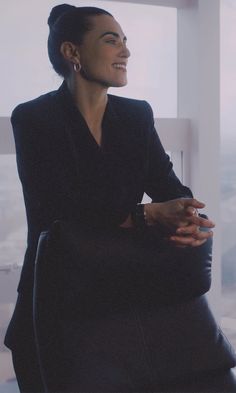 a woman sitting in a chair with her arms crossed and looking off into the distance