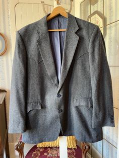 This jacket comes from Circle S in Dallas, Texas, and is made from a blend of 45 per cent acrylic, 30 per cent wool, 20 per cent polyester and five per cent other fibres in a mixture of black, grey and blue tones with a hint of burgundy red. It has the original buttons in the front and on the cuffs, two front pockets and two inside pockets, western styling on the yokes and pockets, and it's fully lined with dark blue silky lining. Marked size 44 regular. The measurements, taken with the jacket lying flat, are: shoulder to shoulder, 19 inches; armpit to armpit, 23 inches; sleeves, 25 inches; length, 32 1/2 inches; bottom edge, 29 inches. In very good condition. Grey Sport Coat, Mens Sport Coat, Houndstooth Jacket, Jacket Blazer, Blazers For Men, Blue Wool, Dallas Texas, Blue Tones, Western Style