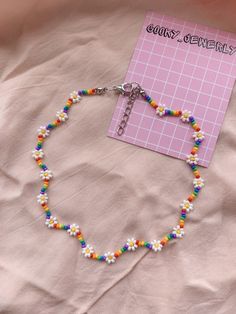 a colorful beaded bracelet on a pink sheet with a note attached to the clasp