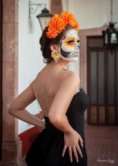 a woman with makeup painted to look like a skeleton and flowers in her hair is posing for the camera