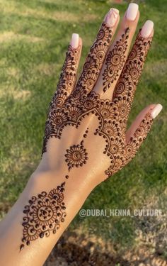 a woman's hand with henna tattoos on it, showing the intricate design