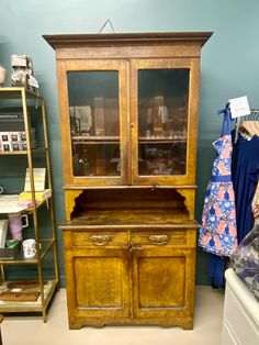 an old wooden china cabinet with glass doors and drawers in a room filled with other items