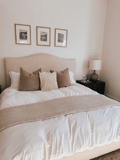 a bed with white sheets and pillows in a bedroom next to two pictures on the wall