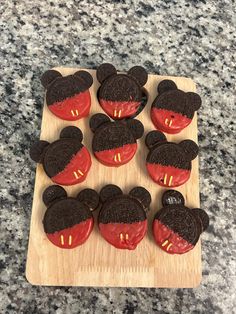 mickey mouse cupcakes with red frosting and chocolate decorations on a cutting board