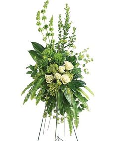 an arrangement of flowers and greenery on a stand