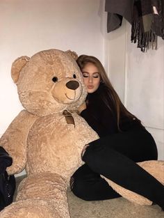 a woman sitting next to a giant teddy bear