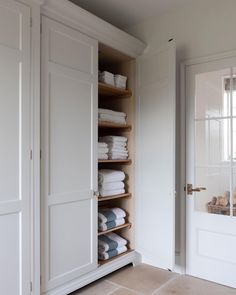 the closet is full of folded towels and linens in white, with open doors leading to another room