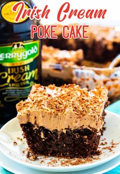 a piece of irish cream poke cake on a white plate with a bottle in the background