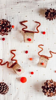 paper bags with faces made to look like christmas decorations and pine cones on a white tablecloth