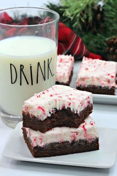 chocolate brownies with white frosting and peppermint on top, next to a glass of milk