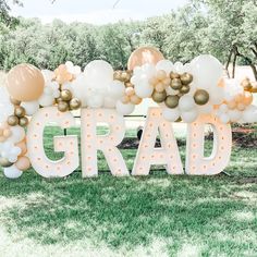 a large sign that says grad with balloons on it in front of some grass