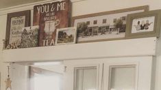 a kitchen with white cupboards and pictures on the wall above it's door