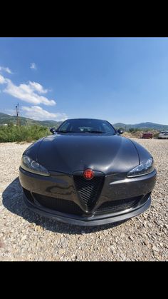 a black sports car is parked on the gravel