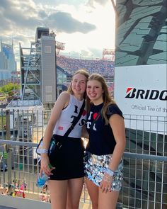 two girls standing next to each other in front of a stadium