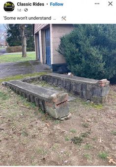 an old concrete bench sitting in front of a building with moss growing on the ground