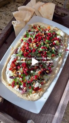 a white plate topped with food on top of a wooden table next to tortilla chips