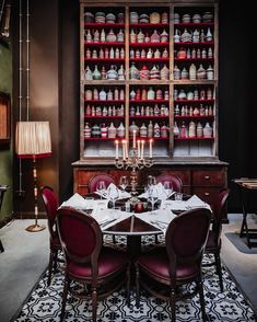 the dining room table is set with red chairs and white linens, while the shelves are full of bottles