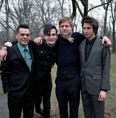 four men in suits posing for the camera