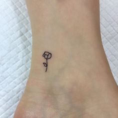 a small rose tattoo on the ankle that is black and white, with a single flower in it