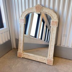 a mirror sitting on top of a floor next to a wall