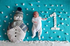 a baby laying on top of a blanket next to a snowman