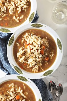 three bowls of chicken and rice soup on top of a blue towel with spoons