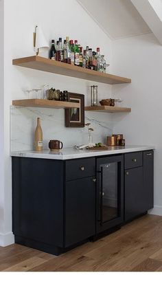 a kitchen with black cabinets and shelves filled with bottles on top of the cupboards